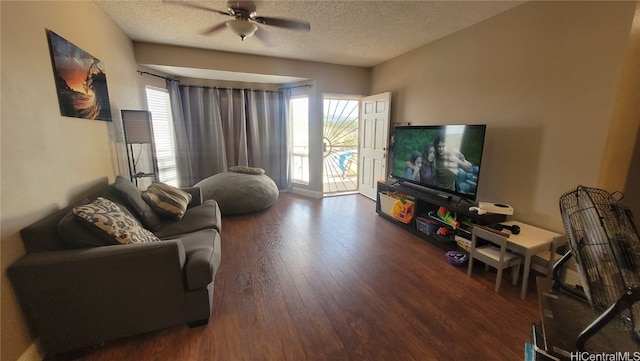 living room featuring a textured ceiling, dark wood-type flooring, and ceiling fan