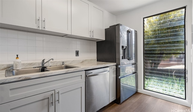 kitchen featuring appliances with stainless steel finishes, sink, white cabinets, dark wood-type flooring, and light stone counters