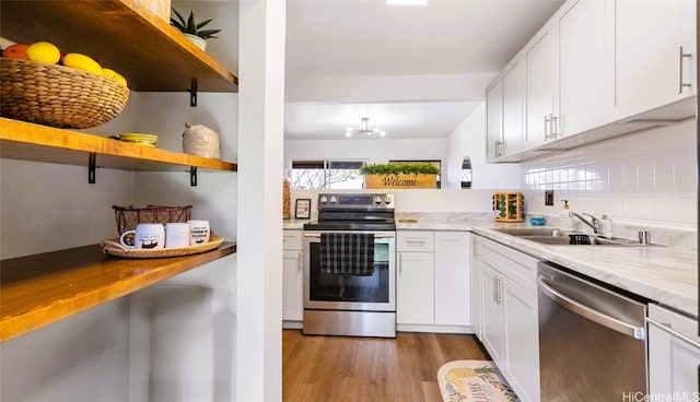 kitchen with appliances with stainless steel finishes, white cabinetry, sink, and light wood-type flooring