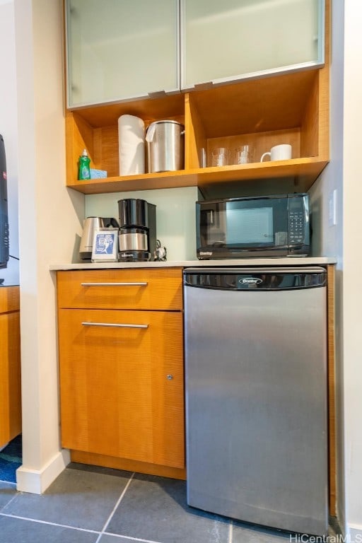 kitchen with stainless steel dishwasher and dark tile patterned flooring