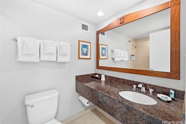 bathroom featuring toilet, tile patterned flooring, sink, and tiled shower