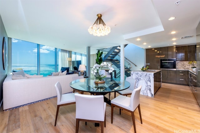 dining area with light hardwood / wood-style floors, a notable chandelier, sink, and floor to ceiling windows