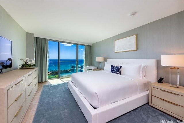 bedroom with a wall of windows, access to exterior, dark wood-type flooring, and a water view