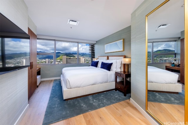 bedroom with multiple windows and hardwood / wood-style flooring