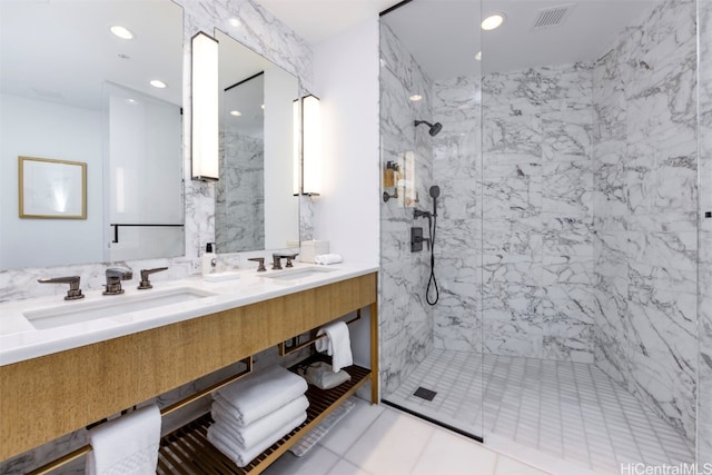 bathroom with vanity, a tile shower, and tile patterned floors