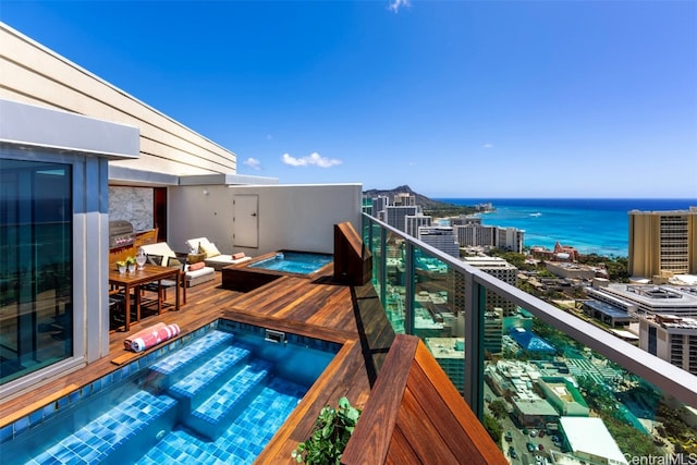 balcony with a water view and an in ground hot tub