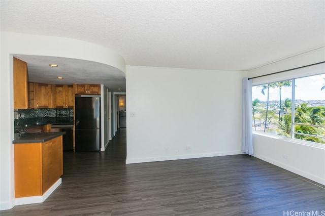 kitchen featuring decorative backsplash, a textured ceiling, dark hardwood / wood-style flooring, and fridge