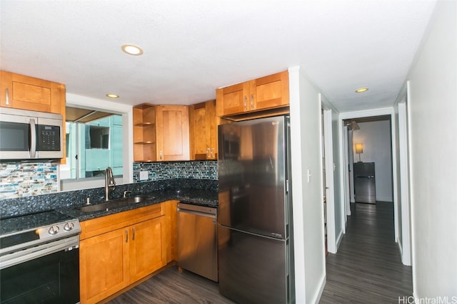 kitchen with dark hardwood / wood-style floors, stainless steel appliances, dark stone countertops, sink, and tasteful backsplash