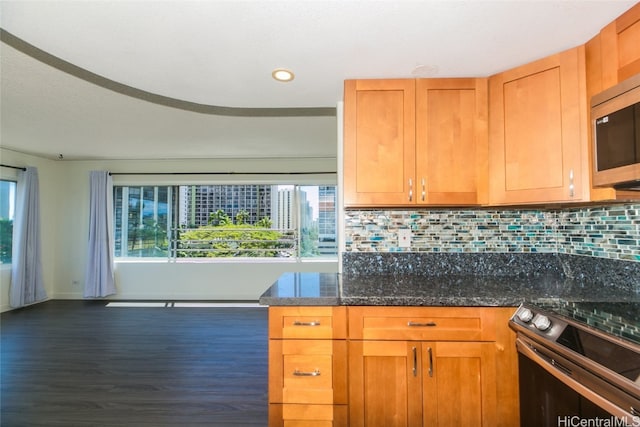 kitchen with dark hardwood / wood-style flooring, appliances with stainless steel finishes, backsplash, and dark stone counters