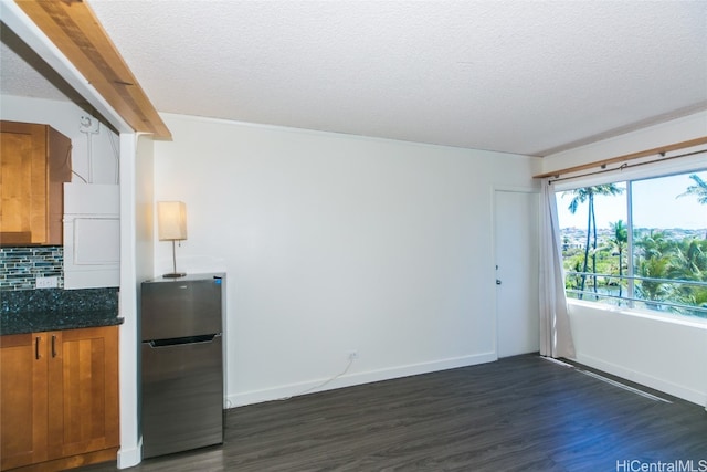 kitchen featuring a textured ceiling, dark hardwood / wood-style floors, backsplash, and stainless steel refrigerator