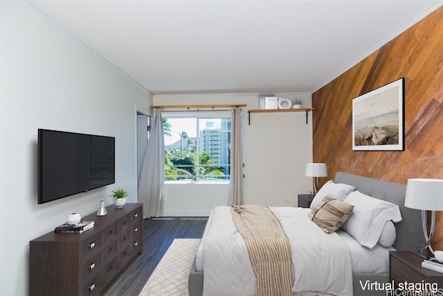 bedroom with dark hardwood / wood-style flooring, a textured ceiling, and wood walls