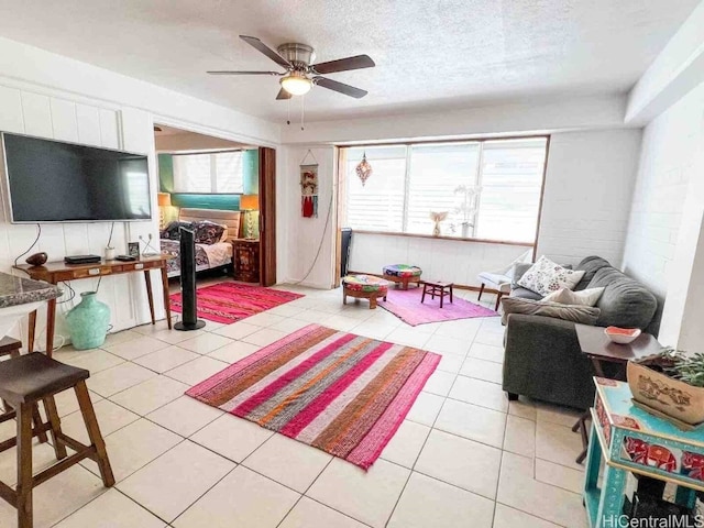 living room with light tile patterned flooring, ceiling fan, and a textured ceiling