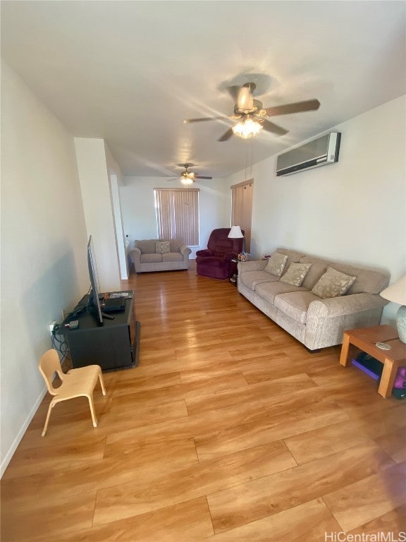 living room featuring ceiling fan, a wall mounted AC, and light wood-type flooring