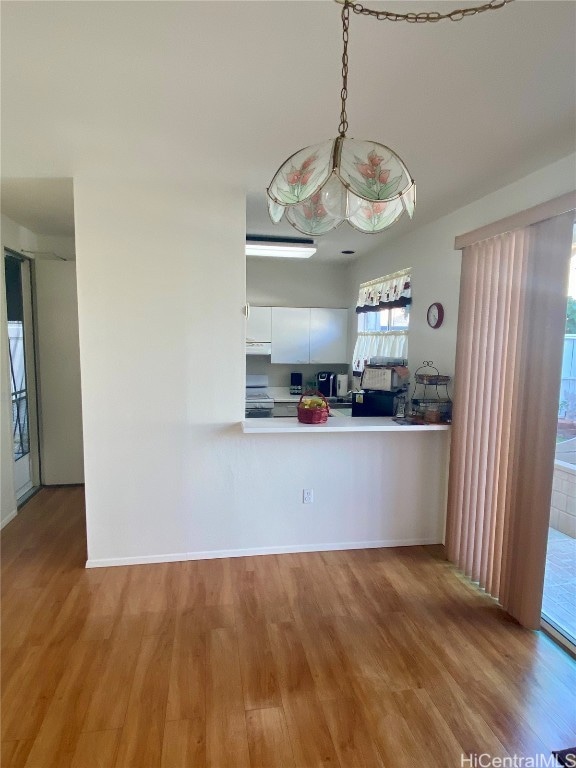 kitchen with electric range oven, white cabinetry, hanging light fixtures, kitchen peninsula, and light hardwood / wood-style flooring