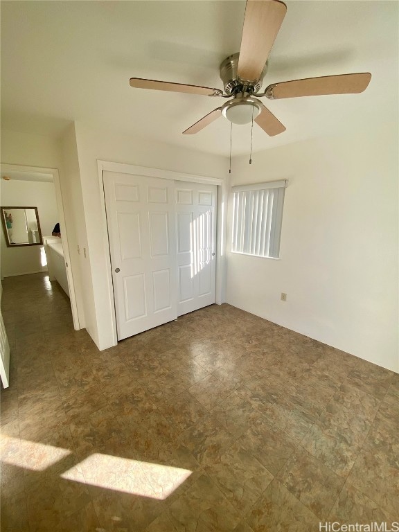 unfurnished bedroom featuring ceiling fan and a closet