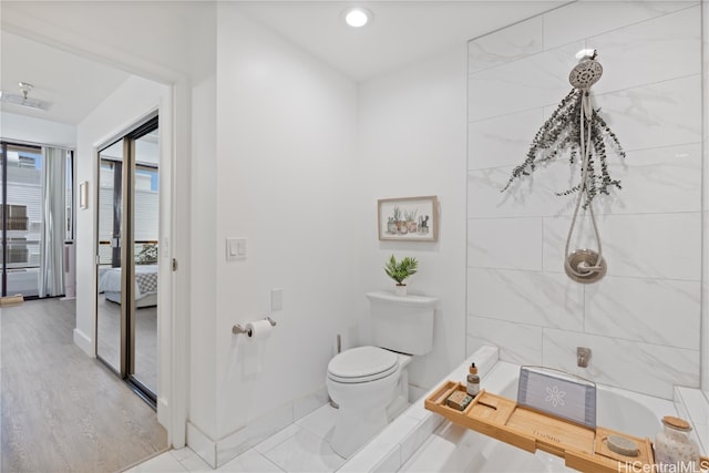 bathroom with a tile shower, toilet, and hardwood / wood-style flooring