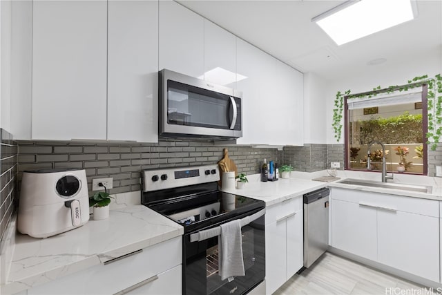 kitchen featuring light stone countertops, appliances with stainless steel finishes, sink, and white cabinets