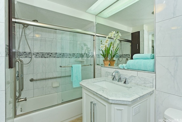 full bathroom with decorative backsplash, bath / shower combo with glass door, tile walls, toilet, and vanity