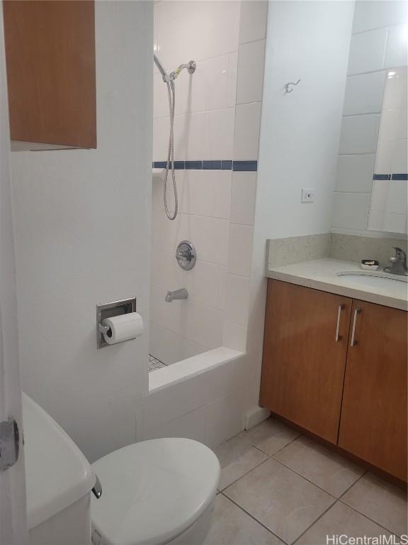 bathroom featuring tile patterned flooring, vanity, a tile shower, and toilet