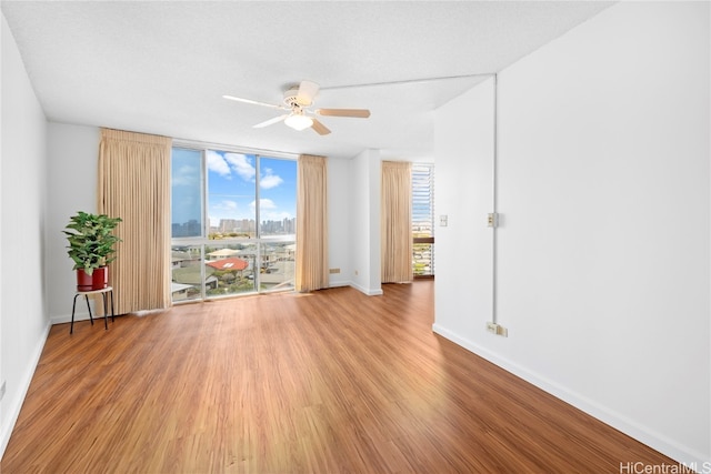 unfurnished room with expansive windows, wood-type flooring, a textured ceiling, and ceiling fan