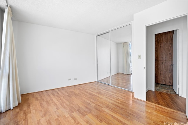 unfurnished bedroom with a closet, a textured ceiling, and wood-type flooring