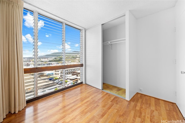 unfurnished bedroom featuring a closet, a textured ceiling, and hardwood / wood-style flooring