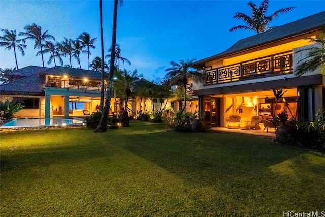 yard at dusk featuring a patio area and a balcony