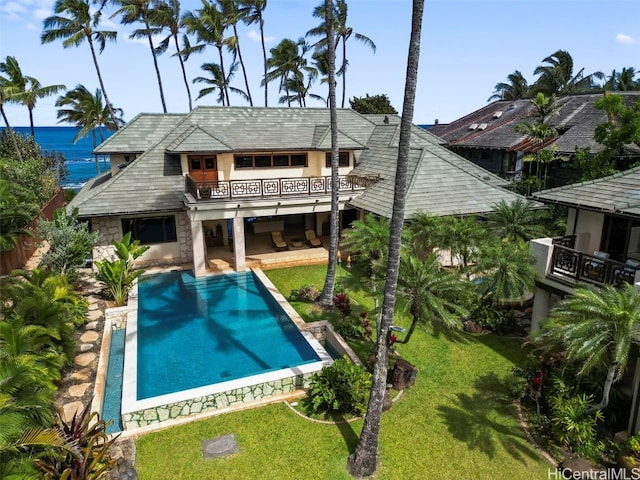 back of property with a patio, a lawn, and a water view