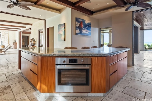 kitchen featuring beamed ceiling, a kitchen island, cooktop, and oven