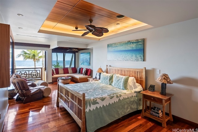 bedroom featuring dark wood-type flooring, ceiling fan, a raised ceiling, and access to exterior