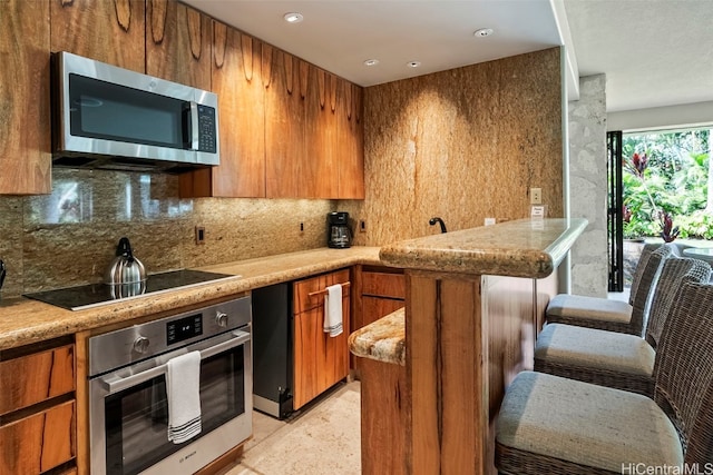 kitchen with light stone counters, stainless steel appliances, and backsplash