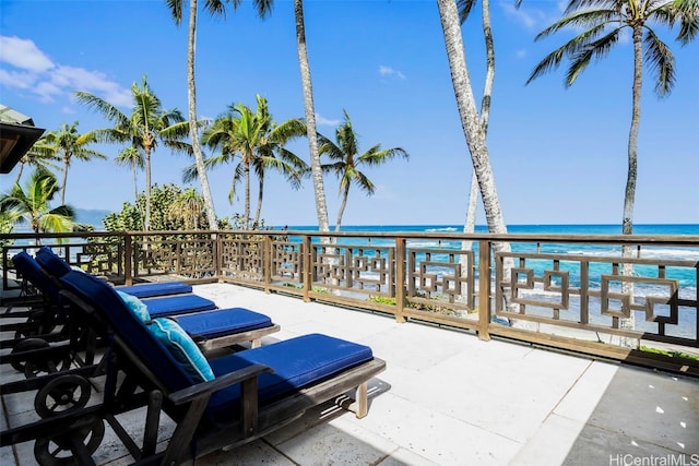 view of patio / terrace with a balcony, a water view, and a beach view