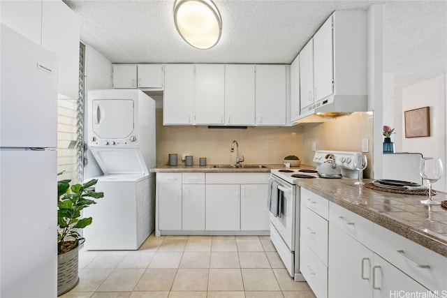 kitchen with sink, white cabinets, stacked washer / dryer, white appliances, and tasteful backsplash