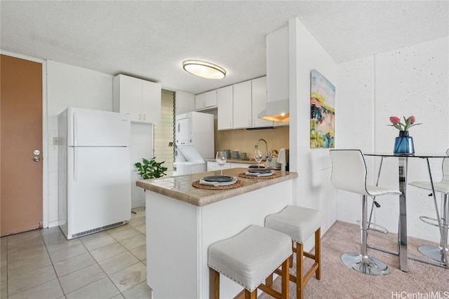 kitchen featuring kitchen peninsula, white cabinetry, a textured ceiling, a kitchen bar, and white fridge