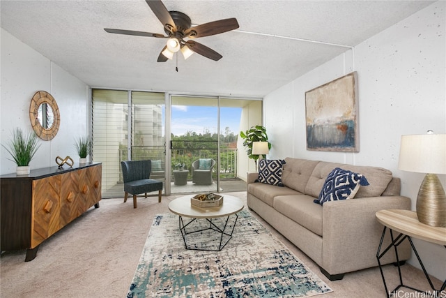 living room with a wall of windows, ceiling fan, a textured ceiling, and light colored carpet