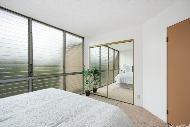 bedroom with a textured ceiling, light colored carpet, and a closet