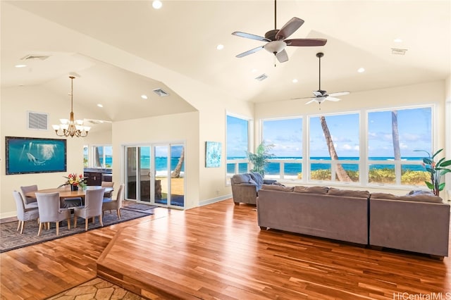 living room with a water view, wood-type flooring, a wealth of natural light, and ceiling fan with notable chandelier