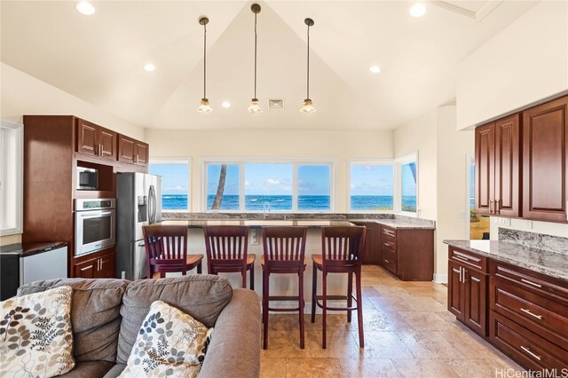 kitchen featuring vaulted ceiling, appliances with stainless steel finishes, light stone counters, and a water view