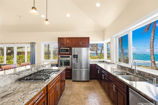 kitchen with lofted ceiling, stainless steel appliances, sink, pendant lighting, and a water view