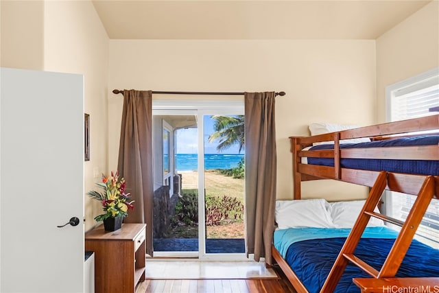 bedroom featuring a water view, light hardwood / wood-style flooring, and access to exterior