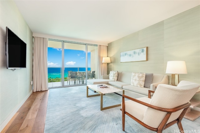 living room featuring a water view, light hardwood / wood-style flooring, and a wall of windows