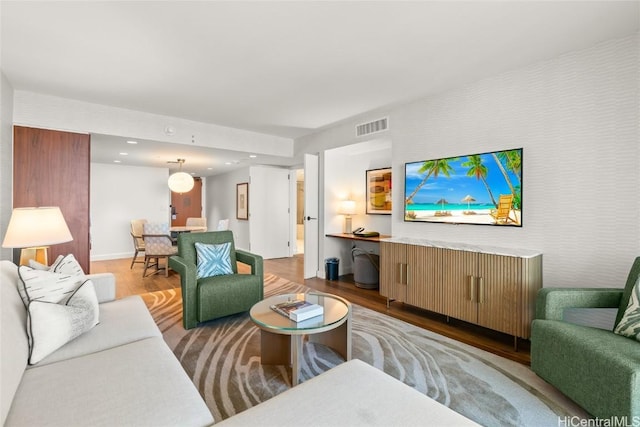 living room with recessed lighting, visible vents, baseboards, and wood finished floors