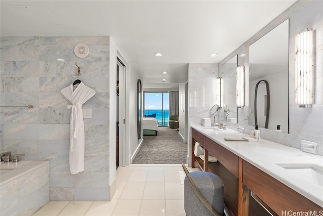 ensuite bathroom with a sink, ensuite bath, tile walls, tile patterned flooring, and double vanity