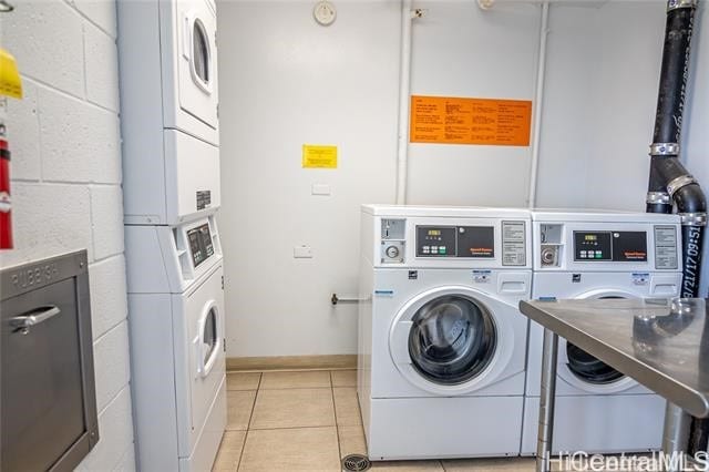 clothes washing area with stacked washing maching and dryer, light tile patterned flooring, and washing machine and dryer