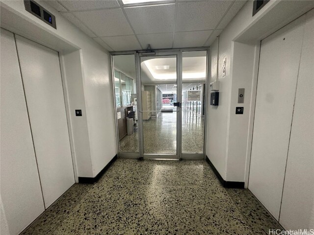 corridor with a paneled ceiling and elevator