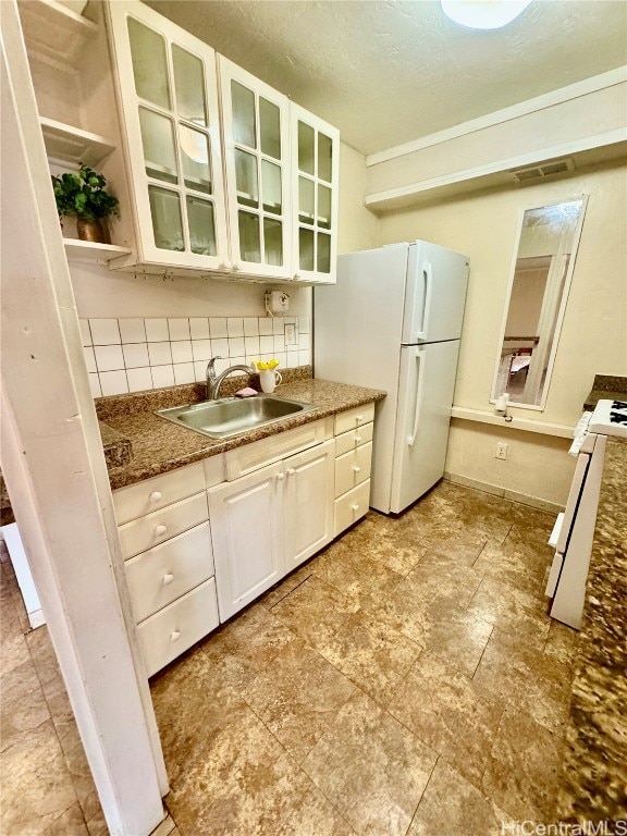 kitchen featuring white cabinets, tasteful backsplash, stone counters, sink, and white appliances