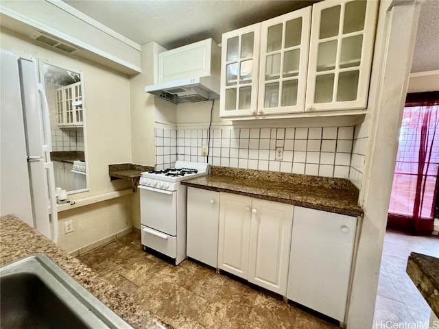 kitchen with white cabinets, tasteful backsplash, dark stone counters, sink, and white appliances