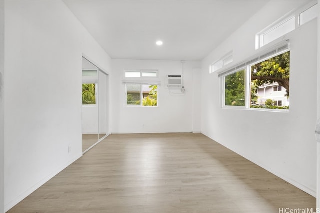 spare room with a wall mounted AC and light hardwood / wood-style floors