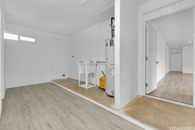 basement with water heater, sink, and light wood-type flooring