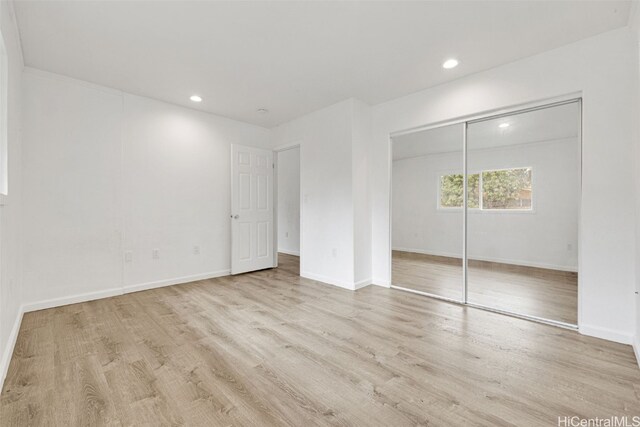 unfurnished bedroom featuring a closet and light wood-type flooring